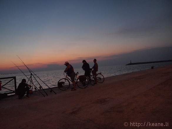 Fishermen along the Rimini pier at sunset